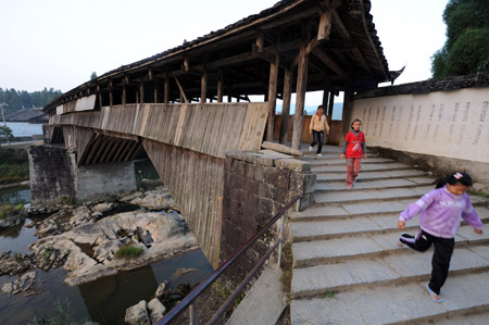 A Village is seen through a window of a roofed wooden arch bridge in Pingnan County of southeast China's Fujian Province, Oct. 16, 2009. [Jiang Kehong/Xinhua]