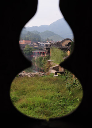 A Village is seen through a window of a roofed wooden arch bridge in Pingnan County of southeast China's Fujian Province, Oct. 16, 2009. [Jiang Kehong/Xinhua]