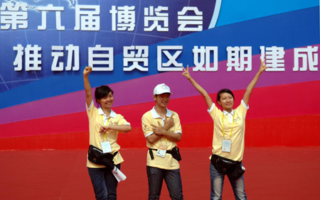 Volunteers pose for a group photo in front of the main exhibition hall of the 2009 China-ASEAN Expo (CAEXPO) at the Nanning International Convention and Exhibition Center in Nanning, capital of southwest China's Guangxi Zhuang Autonomous Region, on Oct. 19, 2009. [Liu Yun/Xinhua]