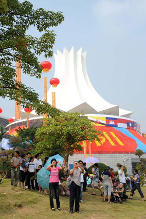 Visitors take photos in front of the main exhibition hall of the 2009 China-ASEAN Expo (CAEXPO) at the Nanning International Convention and Exhibition Center in Nanning, capital of southwest China's Guangxi Zhuang Autonomous Region, on Oct.19, 2009. [Ma Ping/Xinhua]