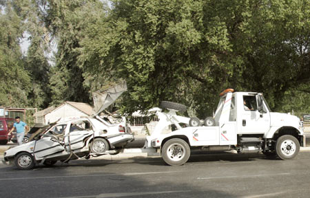 A destroyed vehicle is towed from the site of a bomb attack in Baghdad, October 18, 2009. 