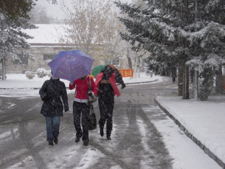 Local residents walk in the snow in Qiqihar City, northeast China's Heilongjiang Province, Oct. 19, 2009. A snowfall hit the city on Monday. [Wang Yunlong/Xinhua]