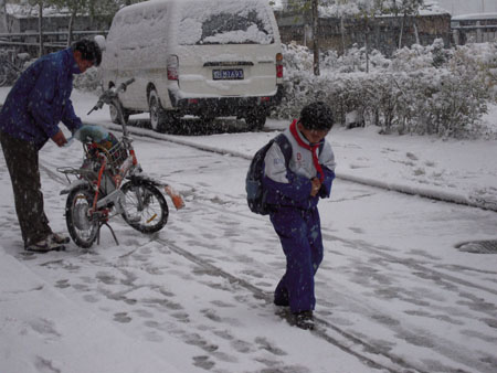 A boy walks in the snow in Qiqihar City, northeast China's Heilongjiang Province, Oct. 19, 2009. A snowfall hit the city on Monday. [Wang Yunlong/Xinhua]