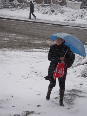 A woman walks in the snow in Qiqihar City, northeast China's Heilongjiang Province, Oct. 19, 2009. A snowfall hit the city on Monday. [Wang Yunlong/Xinhua]