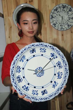 A woman shows a blue-and-white porcelain clock at the exhibition hall of 2009 China Jingdezhen International Ceramic Fair in Jingdezhen, east China's Jiangxi Province, Oct. 18, 2009. The 2009 China Jingdezhen International Ceramic Fair kicked off here on Oct. 18. [Shi Weiming/Xinhua]