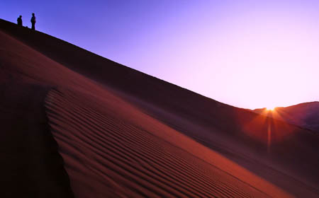 Tourists view sunrise in Badain Jaran Desert located in Araxan League of north China's Inner Mongolia Autonomous Region, Oct. 17, 2009. [Li Xin/Xinhua]