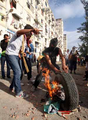 Protesters ignite a tyre during clashes with riot police at Diar Echams district in Algeries, capital of Algeria, Oct. 20, 2009.[Xinhua] 