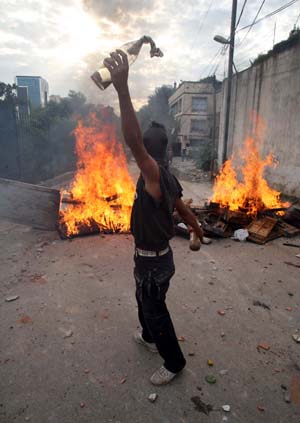 A protester holding bottles confronts with riot police during clashes at Diar Echams district in Algeries, capital of Algeria, Oct. 20, 2009. [Xinhua]