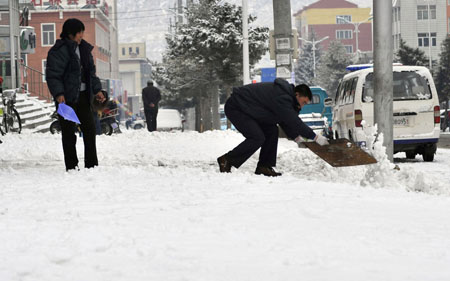 Local residents clear snow on the road in Hexigten Banner, north China's Inner Mongolia Region, Oct. 20, 2009. A snowfall hit the area on Tuesday.[Xinhua]