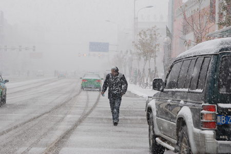 A man walks in the snow on the road in Hexigten Banner, north China's Inner Mongolia Region, Oct. 20, 2009. A snowfall hit the area on Tuesday.[Xinhua]