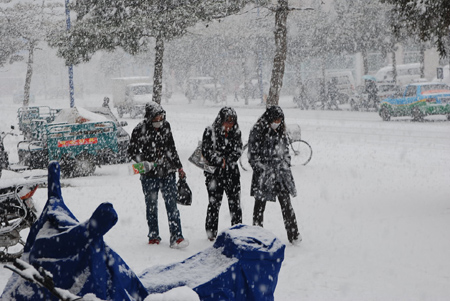 Local residents walk in the snow on the road in Hexigten Banner, north China's Inner Mongolia Region, Oct. 20, 2009. A snowfall hit the area on Tuesday. [Xinhua]