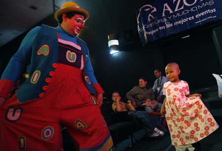 A clown teaches a child who is suffering from cancer to dance during the 14th Mexico International Clown Festival in Mexico City, Mexico, Oct. 20, 2009. [Xinhua]