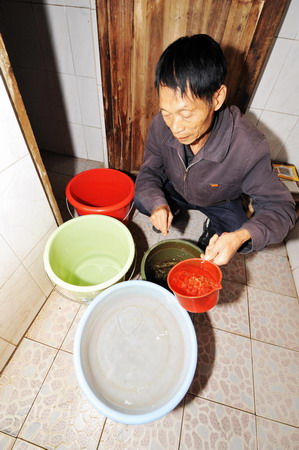 A resident of Yazipu Community of Changsha stores domestic water in a basin and a couple of buckets Oct 20, 2009.
