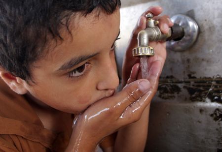 A Palestinian boy drinks water in the southern Gaza Strip town of Rafah Oct. 21, 2009. Palestinians face dire water shortage because of both bad management and Israeli restrictions. [Xinhua]