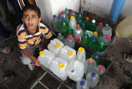 A Palestinian boy fetches drinking water with plastic bottles in the southern Gaza Strip town of Rafah Oct. 21, 2009.[Xinhua]