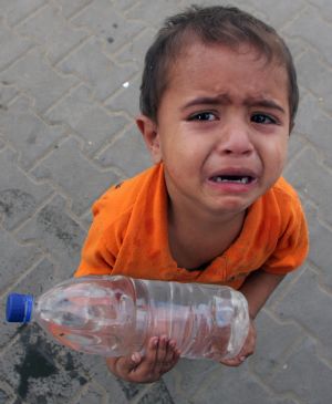 A Palestinian boy cries with a plastic bottle of drinking water in the southern Gaza Strip town of Rafah Oct. 21, 2009.[Xinhua]