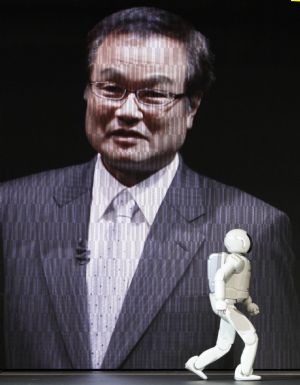 A Honda Motor Co Asimo humanoid robot walks past a projected image of Chief Executive Officer Takanobu Ito during a Honda presentation at the 41st Tokyo Motor Show in Chiba, east of Tokyo, October 21, 2009.[Xinhua/Reuters]