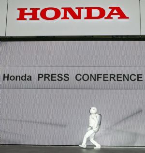 A Honda Motor Co Asimo humanoid robot walks past a video screen during a Honda presentation at the 41st Tokyo Motor Show in Chiba, east of Tokyo, October 21, 2009.[Xinhua/Reuters]