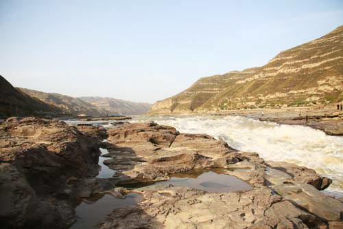 Upriver from Hukou Waterfall, the calm waters of the Yellow River flow smoothly through the distinct huangtu, or 'yellow earth,' landscape east of Yan'an, Shaanxi Province. [CRI]