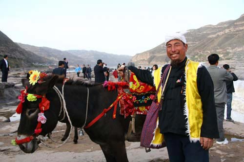  A local farmer who offers donkey rides to tourists poses at Hukou Waterfall east of Yan'an, Shaanxi Province, on Wednesday, October 21, 2009. [CRI]