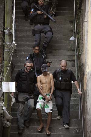  A man suspected of being a member of a drug gang is arrested by police officers in the in the Morro Santo Amaro slum in Rio de Janeiro Oct. 21, 2009. [Xinhua/Reuters]