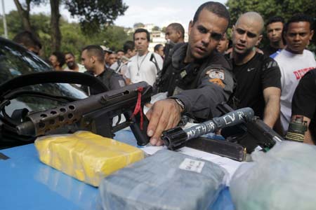 Police officers display drugs and guns found in the Morro Santo Amaro slum in Rio de Janeiro Oct. 21, 2009. [Xinhua/Reuters]