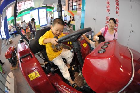 A child plays on an agricultural machine at the Nanning International Convention and Exhibition Center, which is the venue of the 6th China-ASEAN Expo, in Nanning, capital of southwest China's Guangxi Zhuang Autonomous Region, Oct. 24, 2009. The exhibitian hall opened to public on Saturday, the last day of the five-day expo. [Zhou Hua/Xinhua]