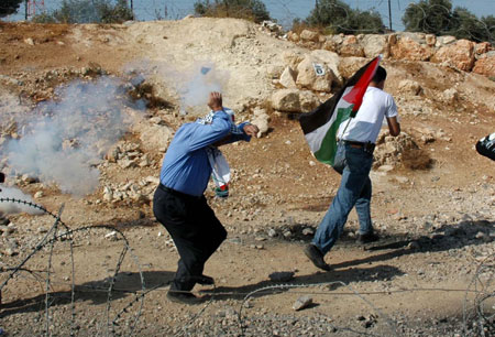 Palestinian demonstrators run to avoid tear gas fired by Israeli troops during a demonstration against Israel's construction of a separation barrier in the West Bank village of Bilin near Ramallah, on 23, 2009. [Nidal Eshtayeh/Xinhua] 