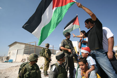 Israeli soldiers stand guard as Palestinian protesters take part in a demonstration against Israel's construction of a separation barrier in the West Bank village of Al-Maasara near Bethlehem, October 23, 2009. [Luay Sababa/Xinhua]