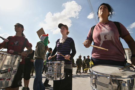 International peace activists play drums in front of Israeli soldiers during in a demonstration against Israel's construction of a separation barrier in the West Bank village of Al-Maasara near Bethlehem, October 23, 2009. [Luay Sababa/Xinhua]