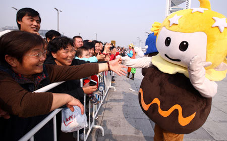 A performer dressed as the mascot of the Tourism Festival interacts with visitors during a parade at the Olympic Park in Beijing, capital of China, on Oct. 23, 2009. [Wang Ying/Xinhua]