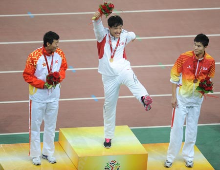 Olympic gold medalist Liu Xiang (C) from Shanghai jubilates while Ji Wei(L) of the People's Liberation Army (PLA) team and Shi Dongpeng from Hebei watch on the podium after the men's 110m hurdles of athletics at the 11th Chinese National Games in Jinan, east China's Shandong Province, Oct. 25, 2009. Liu claimed the title of the event with 13.34 seconds. Ji won the silver while Shi got the bronze.(Xinhua/Li Ga) 