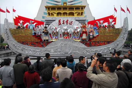 A tripet of female performers in the florid silver costume of Miao ethnic group turns up during the presentation of the Colorful Guizhou Float, which took part in the grand parade in celebration of the 60th anniversary of the founding of the Peoples' Republic of China on the Tian'anmen Square in Beijing, to Guiyang's local citizens on the People's Square of Guiyang, southwest China's Guizhou Province, Oct. 25, 2009. (Xinhua/Ouyang Changpei) 