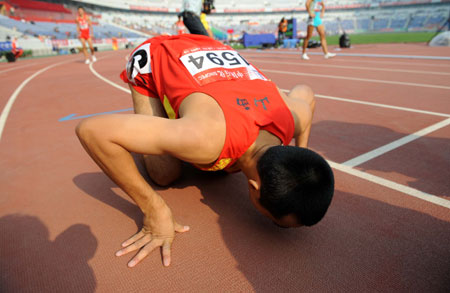 Li Xiangyu from Shanxi kisses the track after the men's 800m final at the 11th Chinese National Games in Jinan, capital of east China's Shandong Province, Oct. 26, 2009. Li Xiangyu won the gold medal with a time of 1 minute and 49.19 seconds. (Xinhua/Fan Changguo)