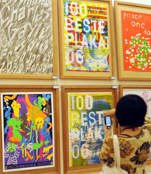 A visitor takes pictures of the exhibited posters during the 4th China International Poster Biennial Exhibition held in Hangzhou, capital of east China's Zhejiang Province, Oct. 26, 2009. A total of 178 poster works were shown in the exhibition, which kicked off at the gallery of China Academy of Art in Hangzhou on Monday.