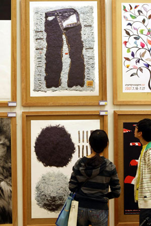 Visitors look at exhibited posters during the 4th China International Poster Biennial Exhibition held in Hangzhou, capital of east China's Zhejiang Province, Oct. 26, 2009. A total of 178 poster works were shown in the exhibition, which kicked off at the gallery of China Academy of Art in Hangzhou on Monday.