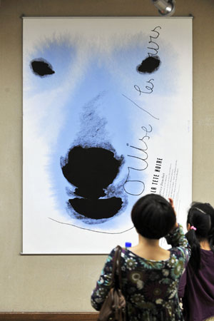 Visitors look at exhibited posters during the 4th China International Poster Biennial Exhibition held in Hangzhou, capital of east China's Zhejiang Province, Oct. 26, 2009. A total of 178 poster works were shown in the exhibition, which kicked off at the gallery of China Academy of Art in Hangzhou on Monday.