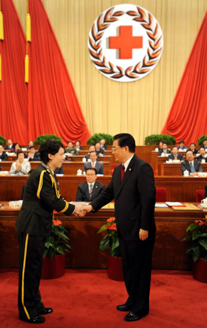 Hu Jintao (R, front), Chinese president and honorary president of the Red Cross Society of China (RCSC), shakes hands with Xian Jishu, a Chinese laureate of the 42nd Florence Nightingale Award, who is a head nurse of the first affiliated hospital of the Third Military Medical University, during the opening ceremony of the 9th national conference of the RCSC in Beijing, capital of China, Oct. 27, 2009. (Xinhua/Ma Zhancheng)