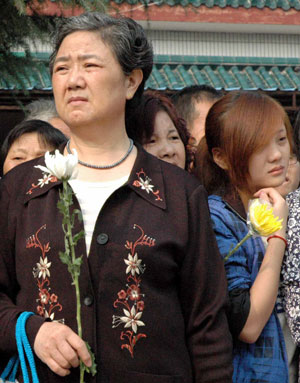 People hold white chrysanthemum during a funeral to mourn for three college students in Jingzhou, a city of central China's Hubei Province, Oct. 28, 2009. A grand memorial service was held here Wednesday to honor three college students, Chen Jishi, He Dongxu and Fang Zhao, who died when rescuing two children from the Yangtze River on Oct. 24. Thousands of people took part in the funeral to see off the three teenagers, all 19-year-old students from the Yangtze University based in Jingzhou City. 