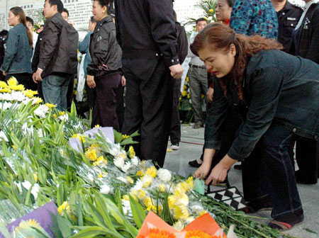 A woman lay flowers in the Jingzhou Memorial House to mourn for three college students in Jingzhou, a city of central China's Hubei Province, Oct. 28, 2009. A grand memorial service was held here Wednesday to honor three college students, Chen Jishi, He Dongxu and Fang Zhao, who died when rescuing two children from the Yangtze River on Oct. 24. Thousands of people took part in the funeral to see off the three teenagers, all 19-year-old students from the Yangtze University based in Jingzhou City. 