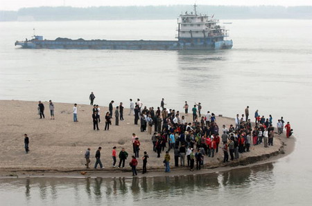 People gather by the Yangtze River in Jingzhou to mourn three deceased students who sacrificed their lives to save two drowning children on Oct 27, 2009.[CFP]