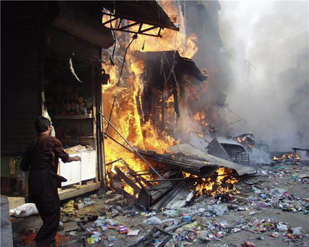 A man stands beside a building at the site of an explosion in northwest Pakistan's city of Peshawar, Oct. 28, 2009. At least 80 people were killed and more than 200 others injured in a powerful bomb blast at a crowded market in Peshawar on Wednesday.