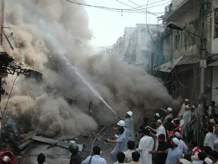 Firefighters try to put out a fire at the site of an explosion in northwest Pakistan's city of Peshawar, Oct. 28, 2009. At least 80 people were killed and more than 200 others injured in a powerful bomb blast at a crowded market in Peshawar on Wednesday.