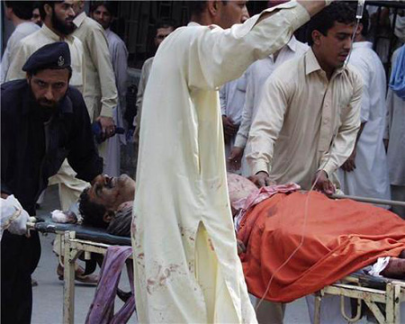 Rescue workers move an injured person at the site of an explosion in northwest Pakistan's city of Peshawar, Oct. 28, 2009. At least 80 people were killed and more than 200 others injured in a powerful bomb blast at a crowded market in Peshawar on Wednesday.