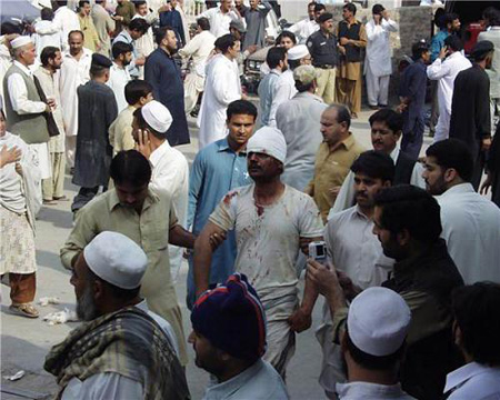 A rescue worker supports an injured person at the site of an explosion in northwest Pakistan's city of Peshawar, Oct. 28, 2009. At least 80 people were killed and more than 200 others injured in a powerful bomb blast at a crowded market in Peshawar on Wednesday.