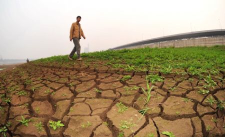 A man walks on the riverbed of Xiangjiang River in Changsha, capital of central China's Hunan Province, Oct. 28, 2009. The waterlevel of Xiangjiang River reached 25 meters on Wednesday, the lowest in history, due to short rainfall. [Xinhua]