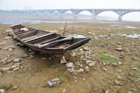 A boat is seen on the riverbed of Xiangjiang River in Changsha, capital of central China's Hunan Province, Oct. 28, 2009. The waterlevel of Xiangjiang River reached 25 meters on Wednesday, the lowest in history, due to short rainfall. [Xinhua]