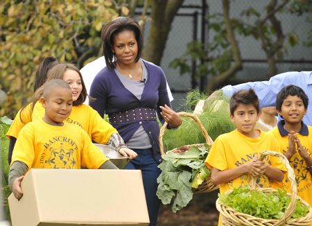 U.S. first lady Michelle Obama and students invited to take part in the harvesting carry their gains during the Fall Harvest of the White House Garden on the South Lawn of the White House in Washington, October 29, 2009.(Xinhua/Zhang Yan)