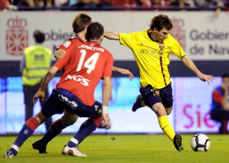 Osasuna's Josetxu Romero (14) tries to block Barcelona's Lionel Messi (R) during their Spanish First Division soccer match at Reyno de Navarra stadium in Pamplona October 31, 2009.