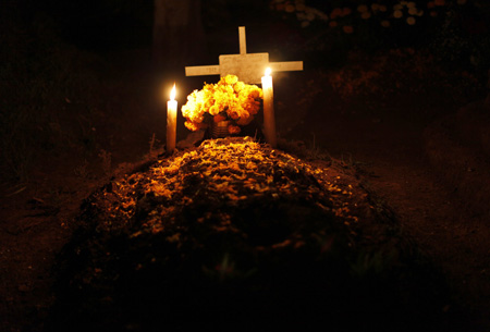 Candles are lit on the grave of a child at the cemetery in Tzintzuntzan, Mexico October 31, 2009.